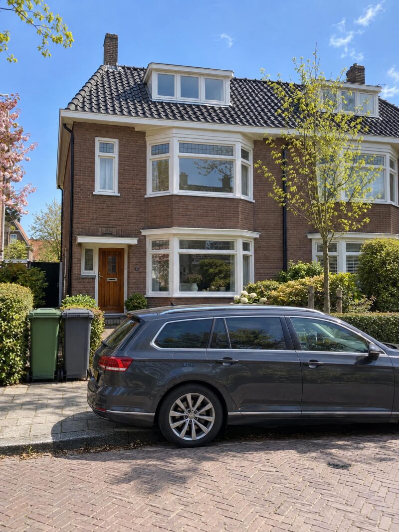 Foto van een huis met een auto en kliko's ervoor