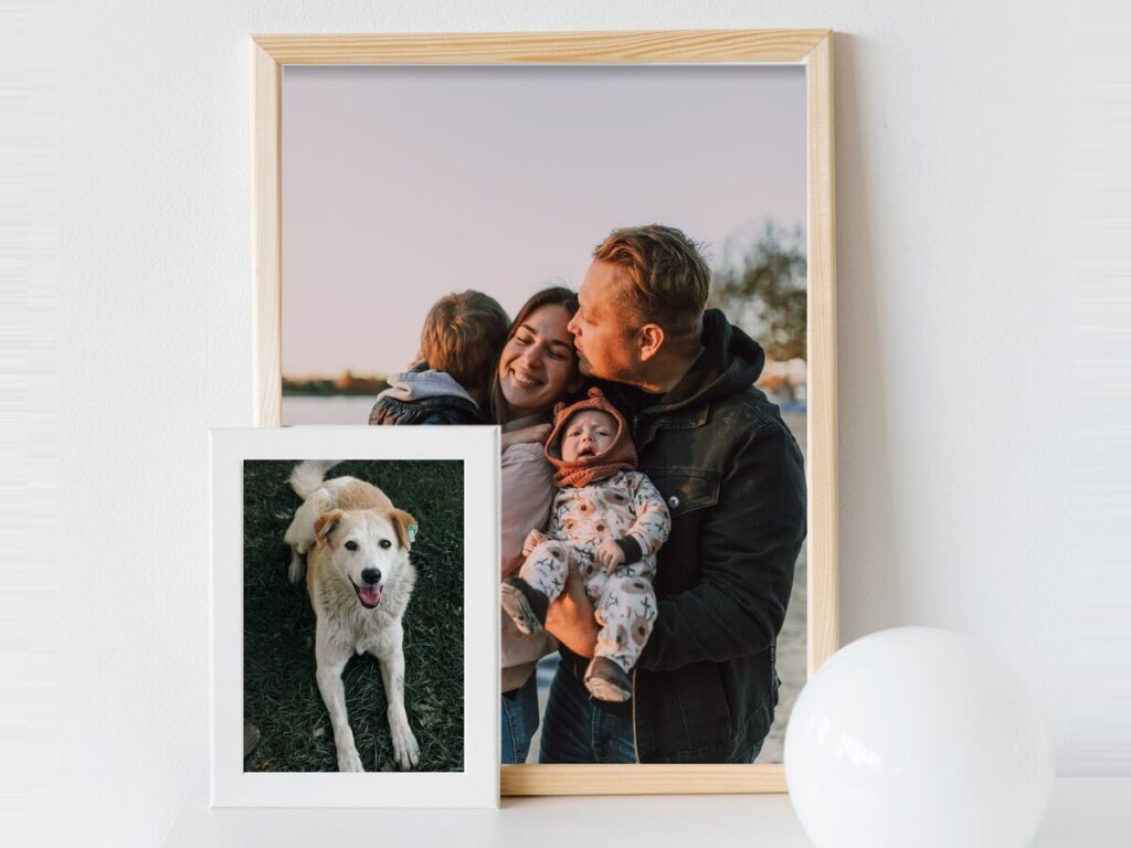 Familieportret in een lichte houten lijst tegen de muur, met een hondenfoto ernaast